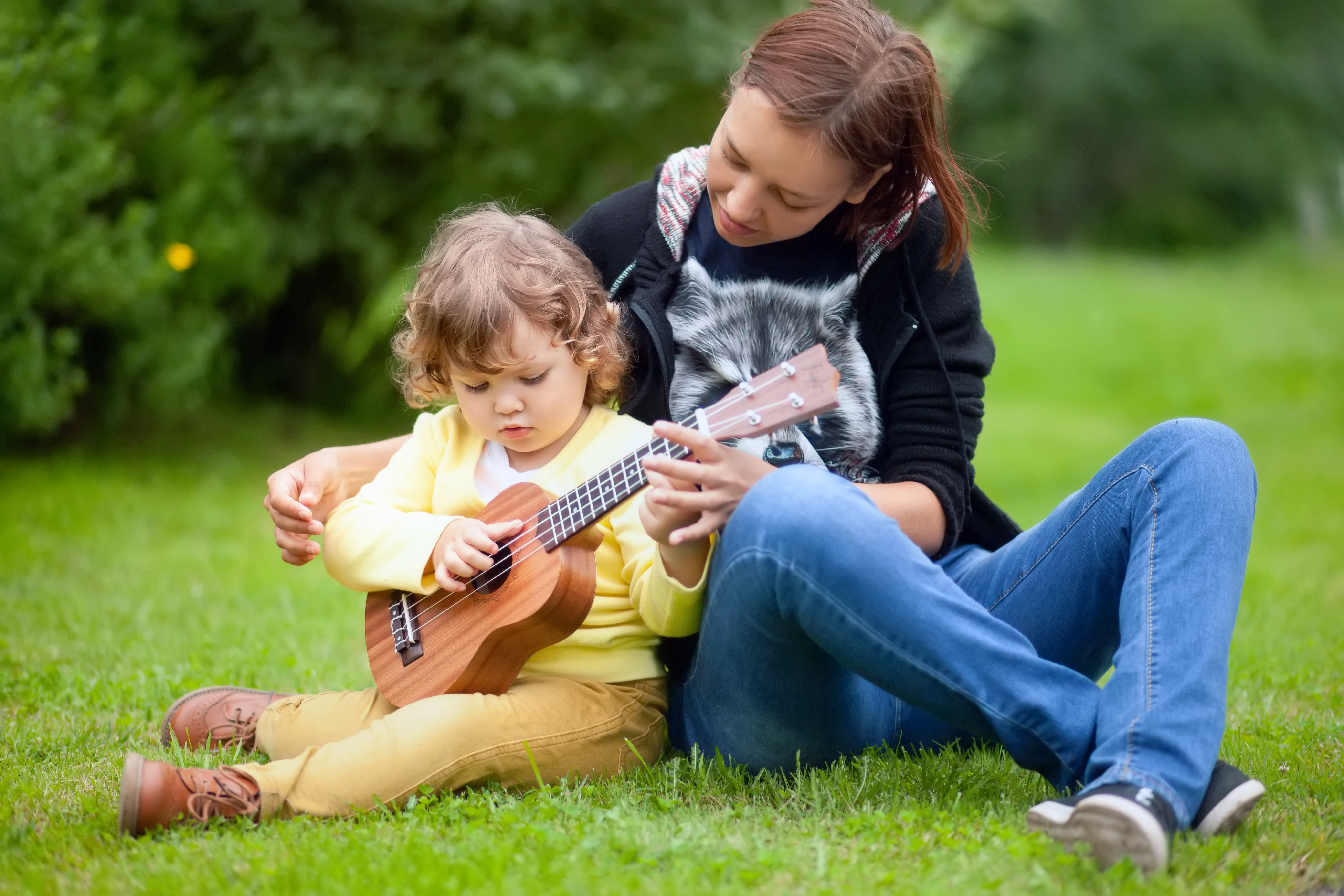 Две девочки играют на гитарах. Дети играют на гитаре весной. Счастливые подростки играют на гитаре. Мальчик учит играть на гитаре с мамой.